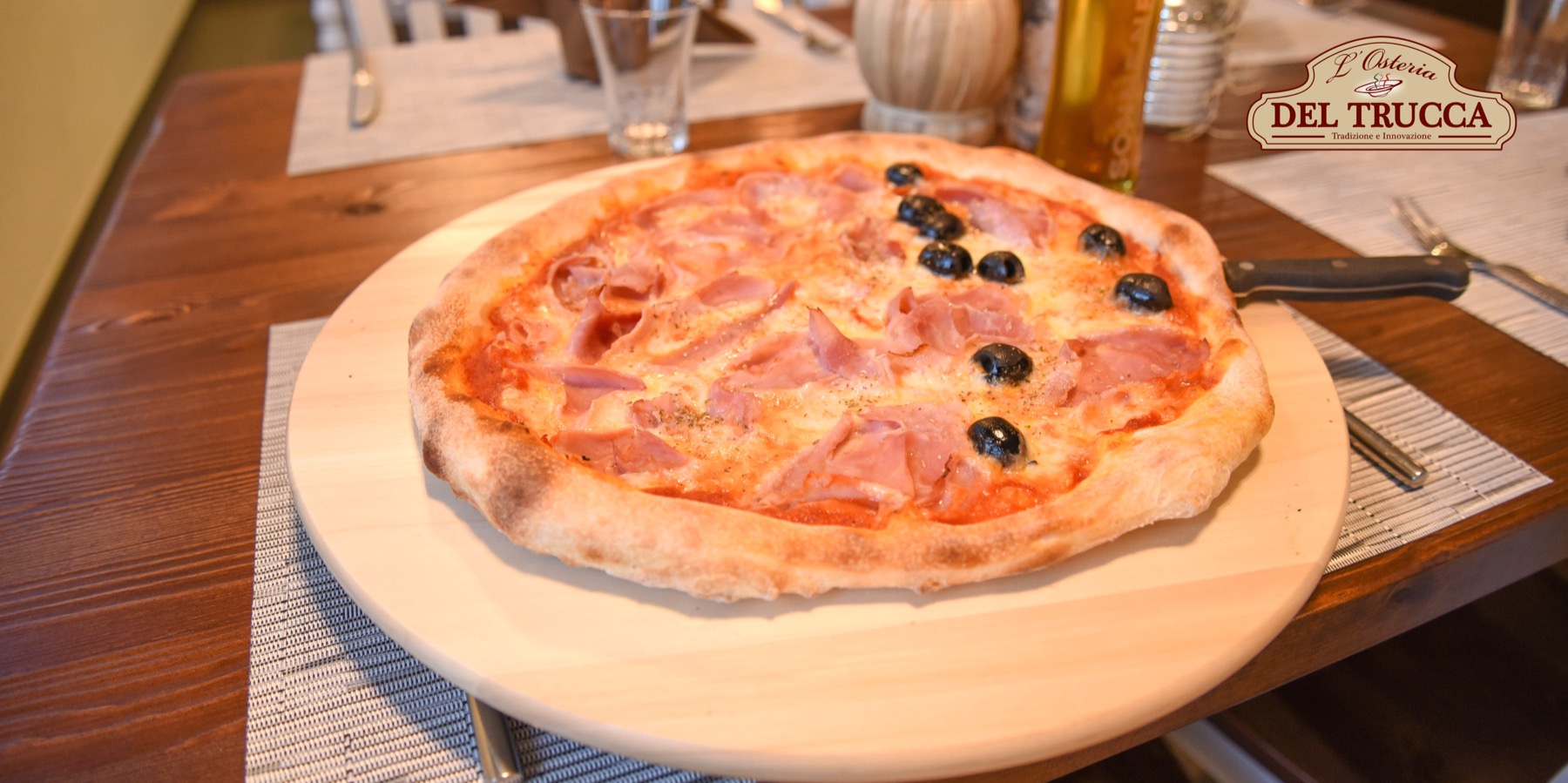 Frisch gebackene Pizza auf rustikalem Holztisch in der Osteria Del Trucca